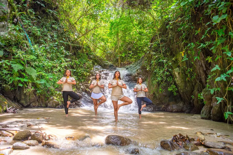Un canyon tropical à Rivera : des femmes en posture d'équilibre dans le lit du ruisseau, entre les parois couvertes de végétation.